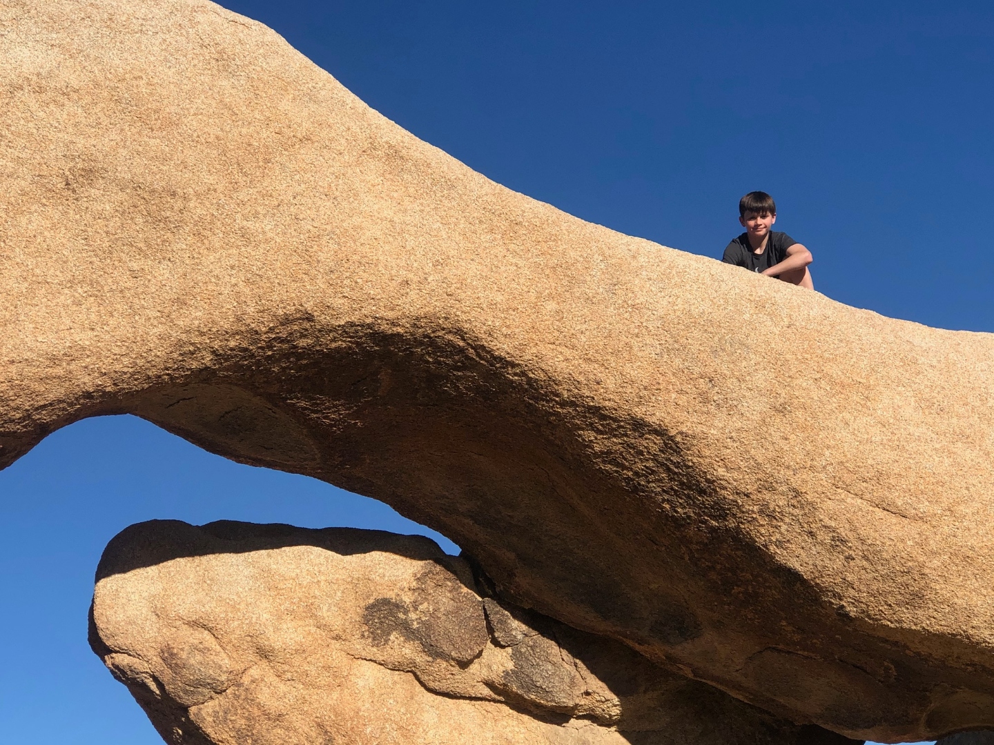 Kid on top of a rock arch in Joshua Tree